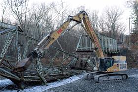 Demolition: A Caterpillar 345C demolition excavator cuts up an old truss bridge. 