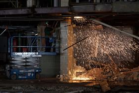 Demolition: A worker uses a torch to cut material out of the ceiling of a structure. 